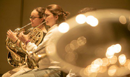 Dos jovenes toca la trompa en una orquesta